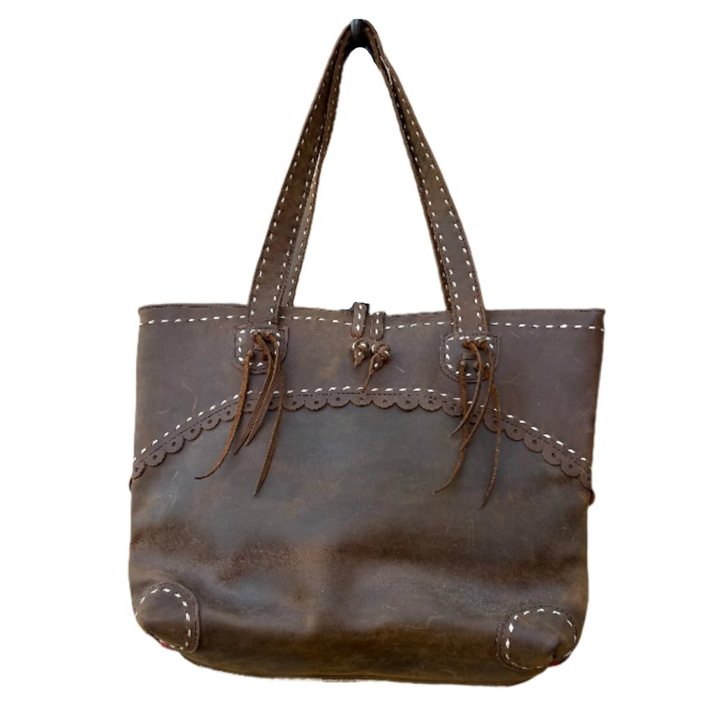 Brown leather handbag with decorative elements on a white background
