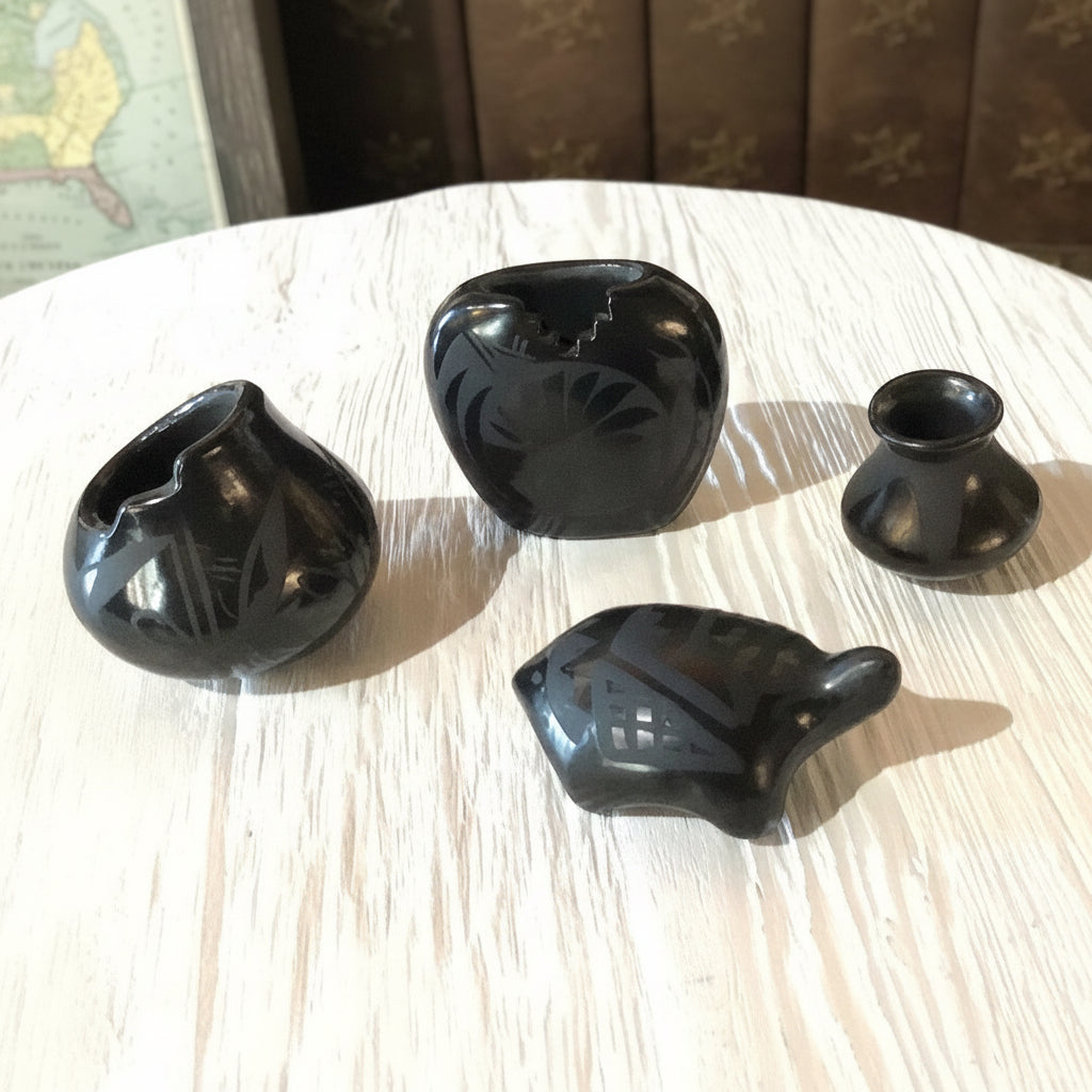 Four black ceramic items on a light wooden surface with a blurred background