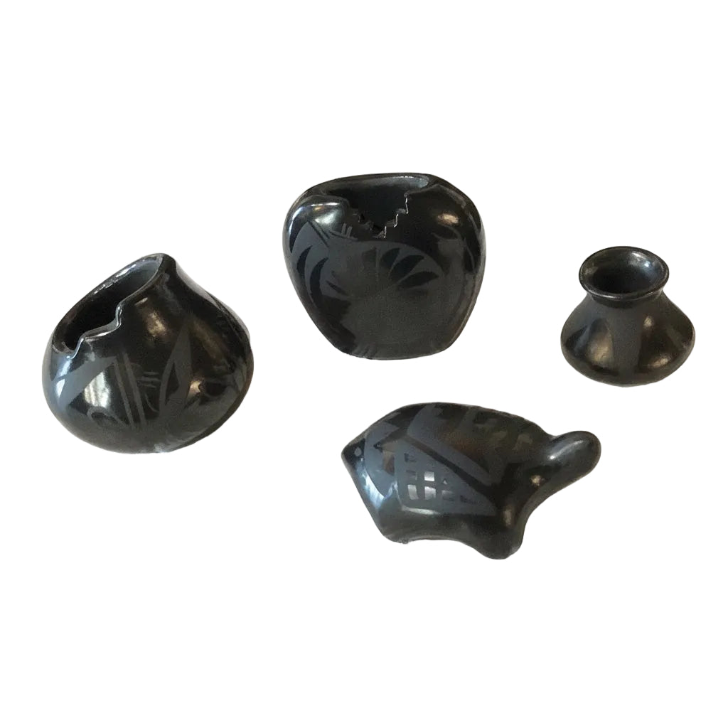 Four black ceramic items on a light wooden surface with a blurred background